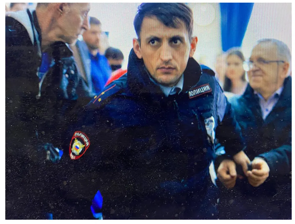 A policeman taking away a Jehovah’s Witness in handcuffs